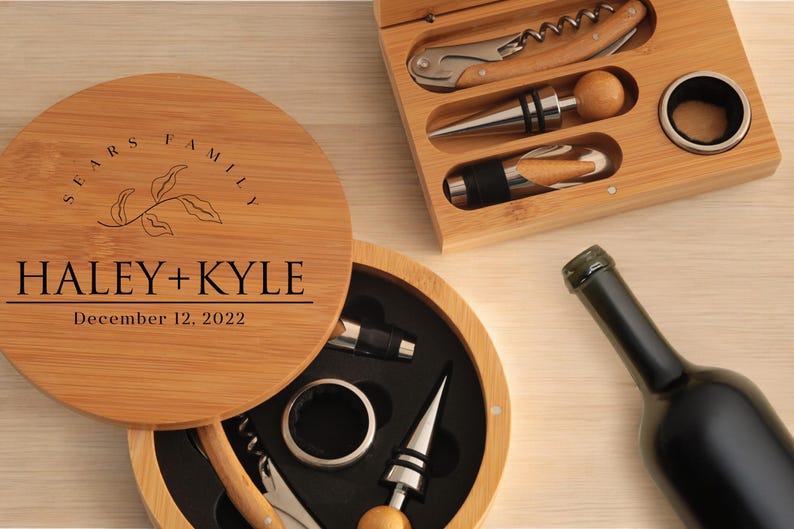 May include: A wooden box with a lid that has the text "SEARS FAMILY HALEY + KYLE December 12, 2022" engraved on it. The box contains a wine opener, a bottle stopper, and a foil cutter.