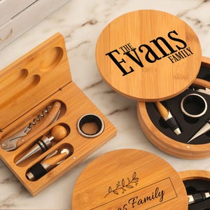 May include: Two wooden boxes with engraved text, one with "The Evans Family" and the other with "[Name] Family". Both boxes contain wine bottle openers, stoppers, and other accessories.