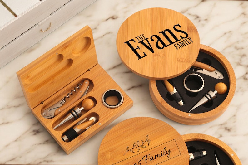 May include: Two wooden boxes with engraved text, one with "The Evans Family" and the other with "[Name] Family". Both boxes contain wine bottle openers, stoppers, and other accessories.