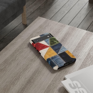 May include: A rectangular smartphone case featuring a patchwork design of triangular fabric segments in red, white, green, yellow, and various shades of blue denim, all joined together with visible white stitching along the edges of each piece.