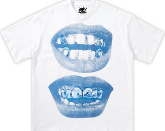 May include: White t-shirt featuring a blue graphic of two sets of lips with teeth. The teeth have a blue and silver design. A small black logo is at the top center of the shirt.