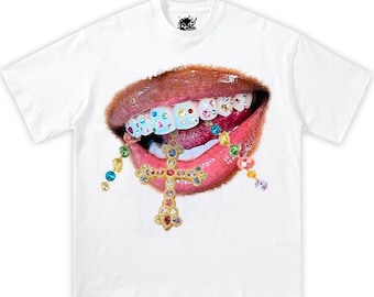 May include: White t-shirt with a graphic of a mouth with jeweled teeth and a gold cross hanging from a colorful beaded chain.