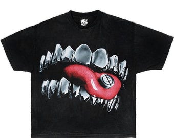 May include: Black t-shirt with a graphic print of a large set of silver teeth with a red tongue sticking out. The tongue has a small silver pill on it.