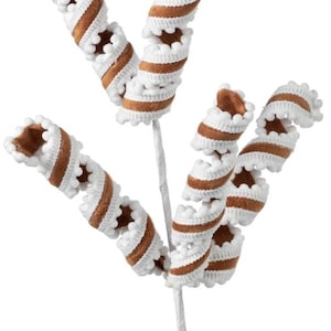 May include: A decorative floral pick featuring three spiraled stems. Each stem is wrapped in brown fabric and edged with white pom-pom trim. The stems are attached to a central white wire base, creating a curled, ribbon-like appearance throughout.