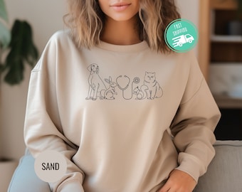 May include: A beige sweatshirt with a black outline of a dog, cat, rabbit, squirrel, and stethoscope. The text "SAND" is on the left sleeve.