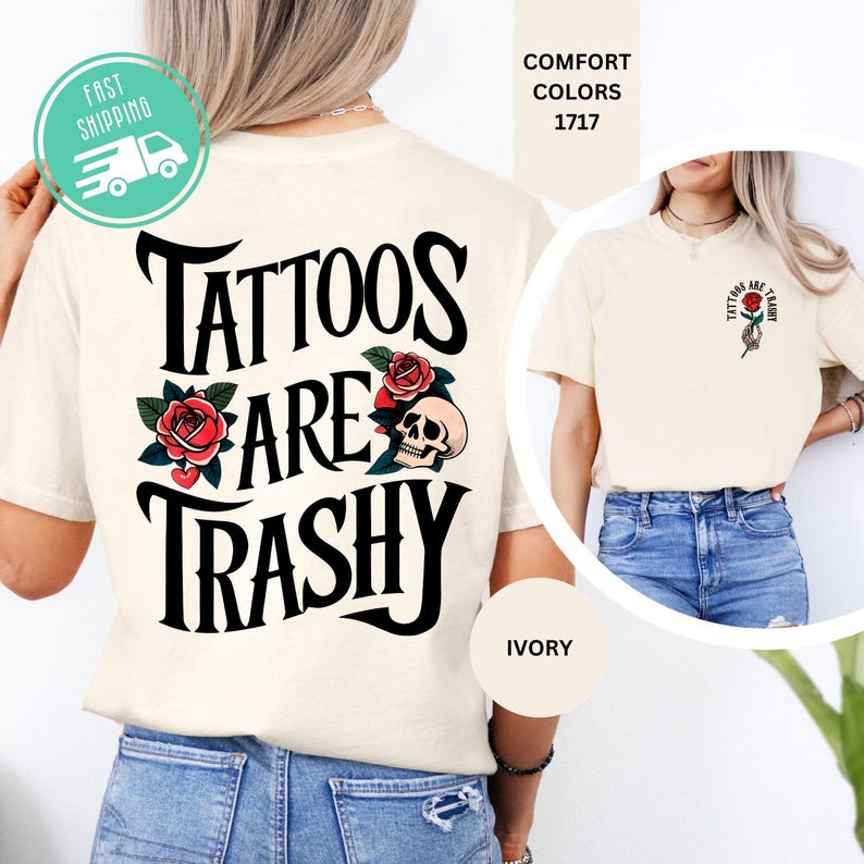 May include: An ivory t-shirt featuring a large black graphic on the back that reads Tattoos Are Trashy, decorated with red roses and a skull. The front chest area displays a smaller matching graphic of a hand holding a red rose with the same text.