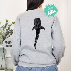 Könnte beinhalten: Ein graues Sweatshirt mit einem schwarzen und weißen Walhai-Motiv auf der Rückseite. Das Sweatshirt ist mit "Athletic Heather" gekennzeichnet.