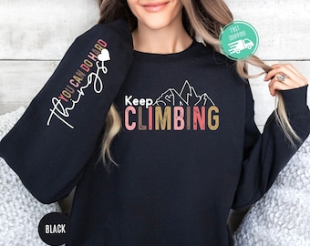 May include: Black sweatshirt with the text "Keep Climbing" in colourful letters and a mountain range graphic. The left sleeve has the text "You Can Do Hard Things" in white with a pink heart.