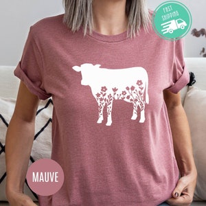 K&ouml;nnte beinhalten: Mauvefarbenes T-Shirt mit einer wei&szlig;en Silhouette einer Kuh mit floralen Details.