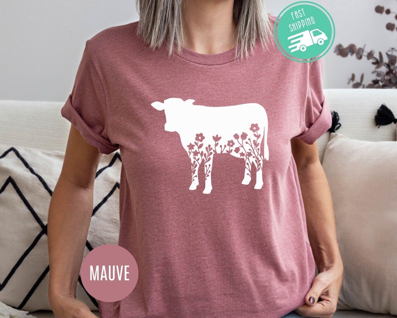 K&ouml;nnte beinhalten: Mauvefarbenes T-Shirt mit einer wei&szlig;en Silhouette einer Kuh mit floralen Details.