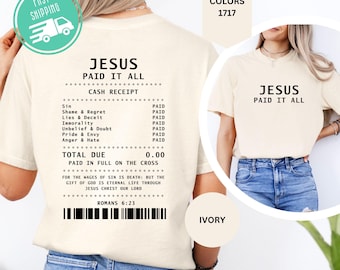 Könnte beinhalten: Ein elfenbeinfarbenes T-Shirt mit einer schwarzen Grafik auf der Rückseite, die wie ein Kassenbon gestaltet ist, mit dem Text JESUS PAID IT ALL, einer Liste bezahlter Sünden und dem Vers Römer 6,23. Vorne steht der Text JESUS PAID IT ALL in Schwarz.