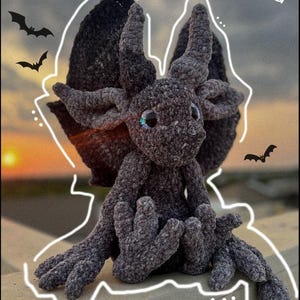 May include: A crocheted gray gargoyle plush toy with large eyes and wings. The toy is sitting on a concrete surface with a sunset in the background. The text 'Ghoul' The Gargoyle' and 'PDF Pattern' are visible in the image.