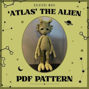 Op de afbeelding: Een gehaakte alien pop in groentinten, met grote ogen en een verdrietige uitdrukking. De afbeelding bevat de tekst "'ATLAS' THE ALIEN" en "PDF PATTERN". De woorden "CREATURE MADE" zijn ook zichtbaar, op een lichtgroene achtergrond.