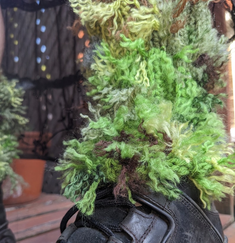 May include: Green, brown, and yellow fuzzy yarn boot cuffs. The cuffs are made of a thick, fluffy yarn and are perfect for adding a touch of whimsy to any outfit.