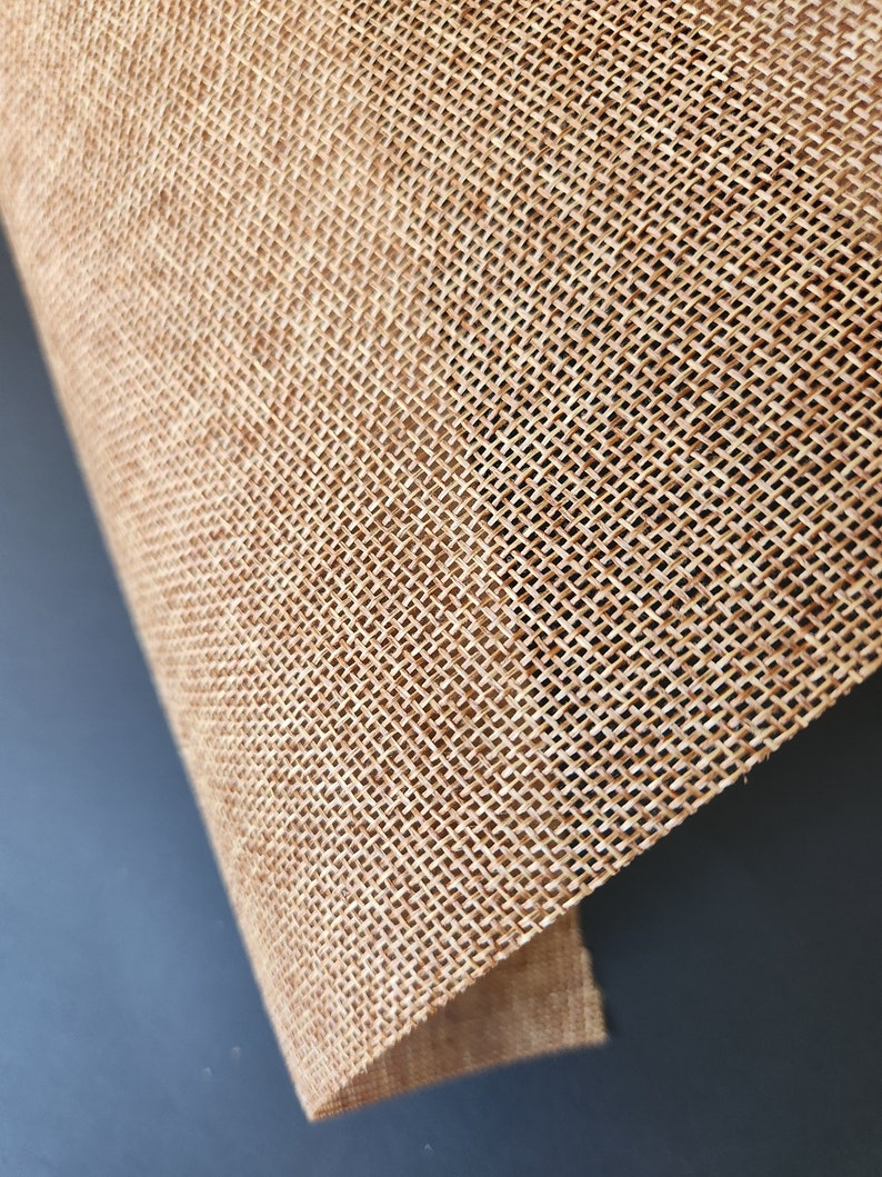 May include: Close-up of a natural brown burlap fabric with a woven texture. The fabric is folded over on itself, showing the underside.