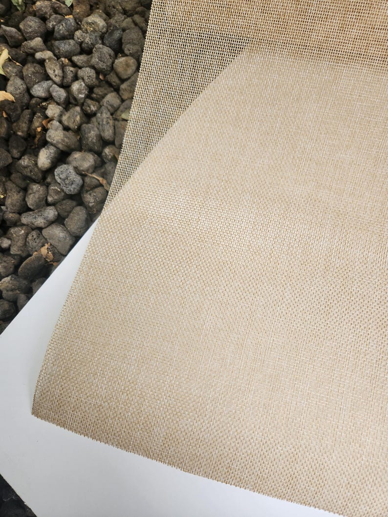 May include: A close-up of a beige woven fabric with a fine mesh texture. The fabric is smooth and has a subtle sheen.