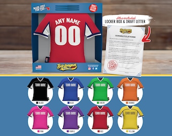 May include: A red, white, and blue personalized jersey pillow with the text "Any Name 00" and the logo "Big League Pillows". The pillow is in a box with a draft letter and locker box. The jersey pillow is also available in black, blue, green, orange, pink, purple, red, and yellow.