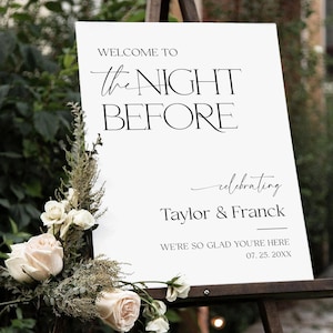 May include: A white welcome sign on a wooden easel, with the text "WELCOME TO the NIGHT BEFORE" in black. The sign also includes the names "Taylor & Franck" and the date "07.25. 20XX". The sign is decorated with white and cream-colored roses.