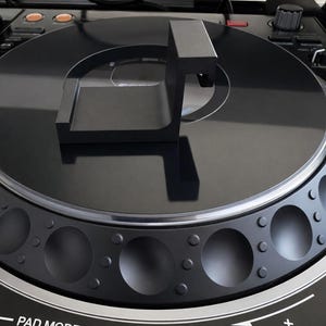 May include: Close-up of a black DJ controller with a circular platter and various buttons. The controller features buttons labeled "SLICER" and "SAMPLER". The design is modern and sleek, with a focus on functionality.