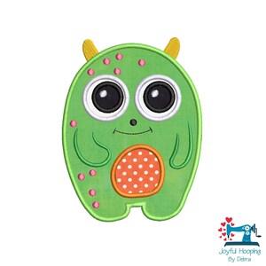 May include: A green monster-like applique with large black and white eyes, yellow horns, and pink spots. The monster has an orange and white polka-dot belly. The image includes the text "Joyful Hooping By Debra".