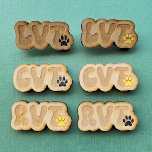 May include: Six wooden tags with the letters LVT, CVT, and RVT, each with a paw print design. The paw prints are black and yellow.