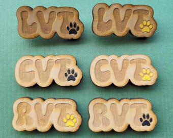 May include: Six wooden tags with the letters LVT, CVT, and RVT, each with a paw print design. The paw prints are black and yellow.