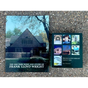May include: Two books about Frank Lloyd Wright. The larger book features a dark brown house on the cover with the text The Oak Park Home and Studio of Frank Lloyd Wright. The smaller book has a dark green cover with six architectural photos.