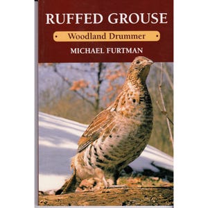 May include: A book cover featuring a ruffed grouse, with the title "RUFFED GROUSE" in white letters on a maroon background. Below the title is "Woodland Drummer" and the author's name, Michael Furtman. The image shows the bird in its natural habitat.