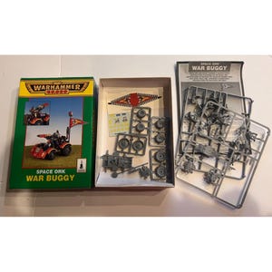 May include: A Warhammer 40,000 Space Ork War Buggy model kit. The box is green and yellow, with an image of the assembled buggy. Inside the box are unassembled plastic parts, wheels, and decals. A separate instruction sheet is also included.