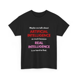 May include: Black t-shirt with the text "Maybe we talk about ARTIFICIAL INTELLIGENCE so much because REAL INTELLIGENCE is so hard to find." The text is in white, red, and pink.