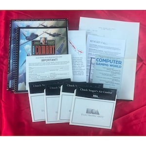 May include: A vintage computer game set, featuring a spiral-bound manual with a cover image of fighter jets and the title "Chuck Yeager's Combat." Includes floppy disks, registration card, and other printed materials. The game is from Electronic Arts.