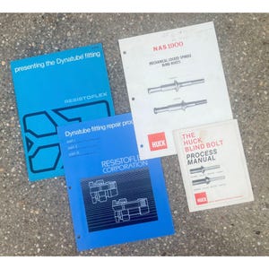 May include: Three technical manuals featuring blue and white covers. One blue manual reads Presenting the Dynatube fitting Resistoflex. Another blue manual reads Dynatube fitting repair procedures Resistoflex Corporation. A white manual reads NAS 1900 Mechanical Locked Spindle Blind Rivets and The Huck Blind Bolt Process Manual.