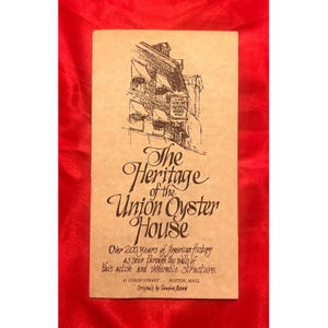 May include: A tan-colored brochure with the title "The Heritage of the Union Oyster House" in elegant script. The brochure features a detailed pen and ink illustration of a building and text describing its history.