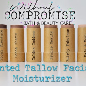 May include: Six brown cardboard tubes with different shades of tinted tallow facial moisturizer. The tubes are labeled with the names: Ebony Elegance, Cocoa Charm, Golden Goddess, Bronze Beauty, Fairly Fabulous, and Pale & Posh. The text "Without Compromise Bath & Beauty Care" is at the top of the image. The text "Tinted Tallow Facial Moisturizer" is at the bottom of the image.