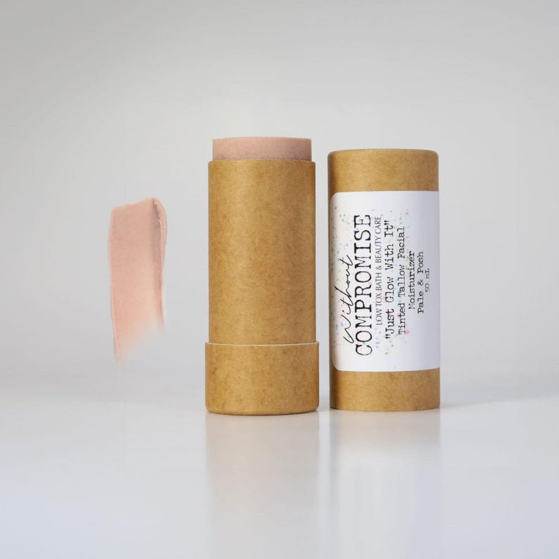 May include: A brown cardboard tube with a white label that reads "Without Compromise Low Tox Bath & Beauty Care "Just Glow With It" Tinted Tallow Facial Moisturizer Pale & Peach 30 ml". The tube contains a pink tinted moisturizer.