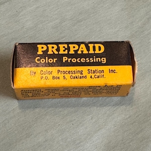 May include: A vintage film processing box with the words "PREPAID Color Processing" in yellow and black. The box is yellow and black with text that reads "By Color Processing Station Inc. P.O. Box 5, Oakland 4, Calif."