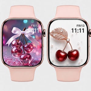May include: Two smartwatches with light pink silicone bands and rectangular screens. The left screen displays three cherries with a pink ribbon and the text FRI13 11:11. The right screen shows two cherries with a jeweled leaf and the text FRI13 11:11.