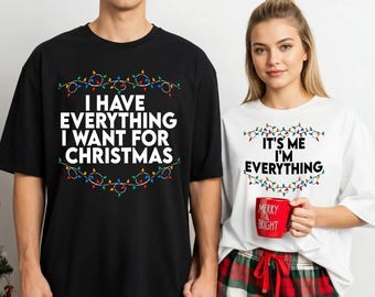 May include: Black t-shirt with the text "I HAVE EVERYTHING I WANT FOR CHRISTMAS" surrounded by a string of Christmas lights. A white t-shirt with the text "IT'S ME I'M EVERYTHING" and a red mug that says "MERRY & BRIGHT".