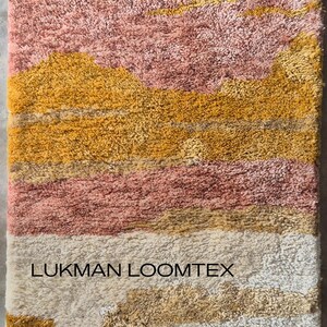 Close-up vertical detail of mid century modern abstract shag rug, plush wool pile in mustard gold, pink, ivory bands.