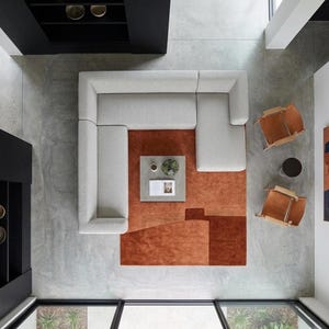 Aerial view over sofa and chairs, terracotta geometric rug anchors this contemporary living space