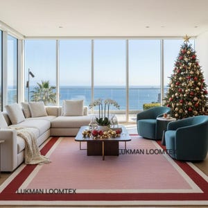 Bright ocean-view living room with white sofa, pink wool area rug anchors seating, minimalist vibe.