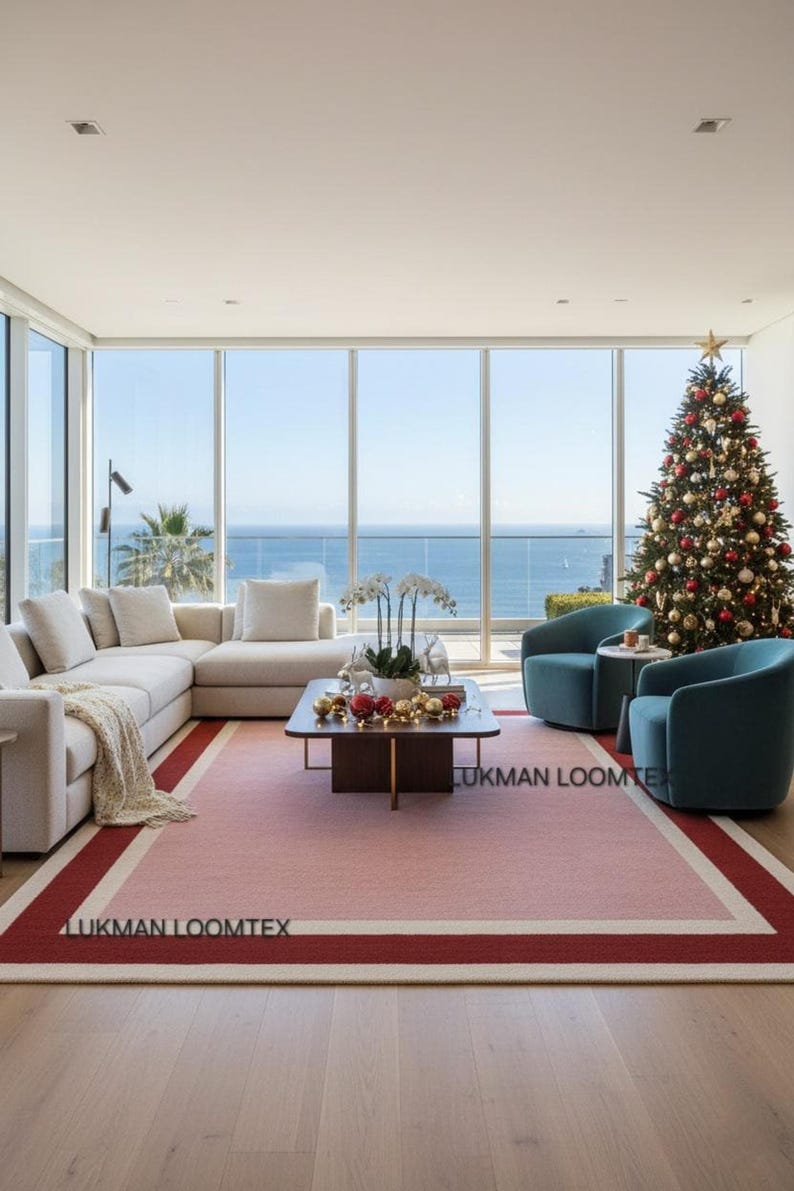 Bright ocean-view living room with white sofa, pink wool area rug anchors seating, minimalist vibe.