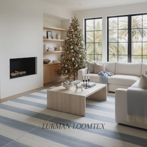 May include: A living room featuring a decorated Christmas tree, a white sofa, and a blue and white striped rug. A wooden coffee table displays ornaments. The text "LUKMAN LOOMTEX" is visible on the rug.