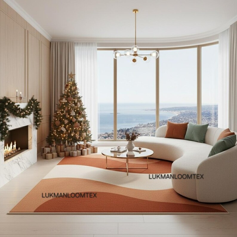 May include: A modern living room with a Christmas tree, fireplace, and a curved white sofa. A rug with a wave design in shades of orange and cream is on the floor. The room has large windows with a view of the ocean.