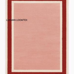 Flat lay showing hand-tufted pink wool area rug, rose center, ivory inner border, burgundy outer.