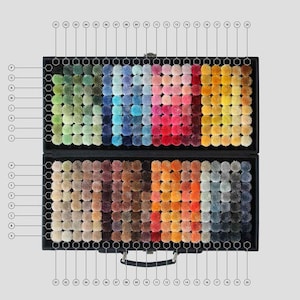 May include: A black case with a handle, open to reveal a collection of colorful carpet samples. The samples are arranged in a grid pattern, showcasing a wide range of hues from greens and blues to reds, oranges, and grays. Each sample is a small, textured square.