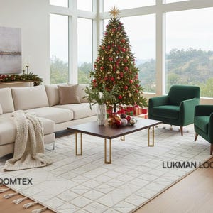 May include: A festive living room featuring a decorated Christmas tree, a beige corner sofa, and two green armchairs. A coffee table with gold legs sits on a patterned rug. The room has large windows and a view of the countryside.