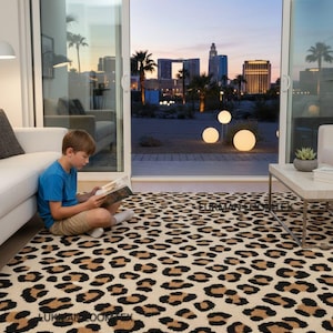 May include: A beige leopard print rug featuring black and brown spots. The rug is in a living room with a city skyline visible through a sliding glass door. A person is sitting on the rug reading a book.