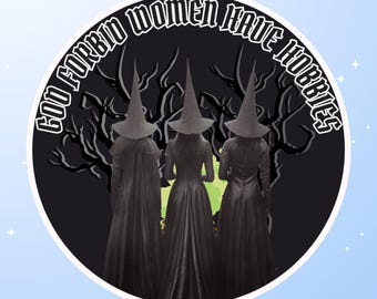 May include: A circular sticker featuring three figures in long dark dresses and pointed hats standing before a dark tree silhouette. The text "GOD FORBID WOMEN HAVE HOBBIES" is arched in white letters along the top edge of the black background.