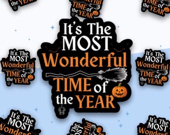 May include: A black sticker with white and orange text that reads It's The MOST Wonderful TIME of the YEAR. The design features a graphic of a witch's broomstick, a smiling jack-o'-lantern, and a small spider hanging from a web.